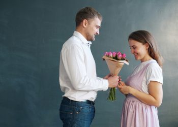 Stijlvolle man in wit overhemd geeft bos roze rozen cadeau