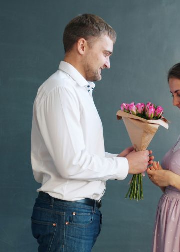 Stijlvolle man in wit overhemd geeft bos roze rozen cadeau